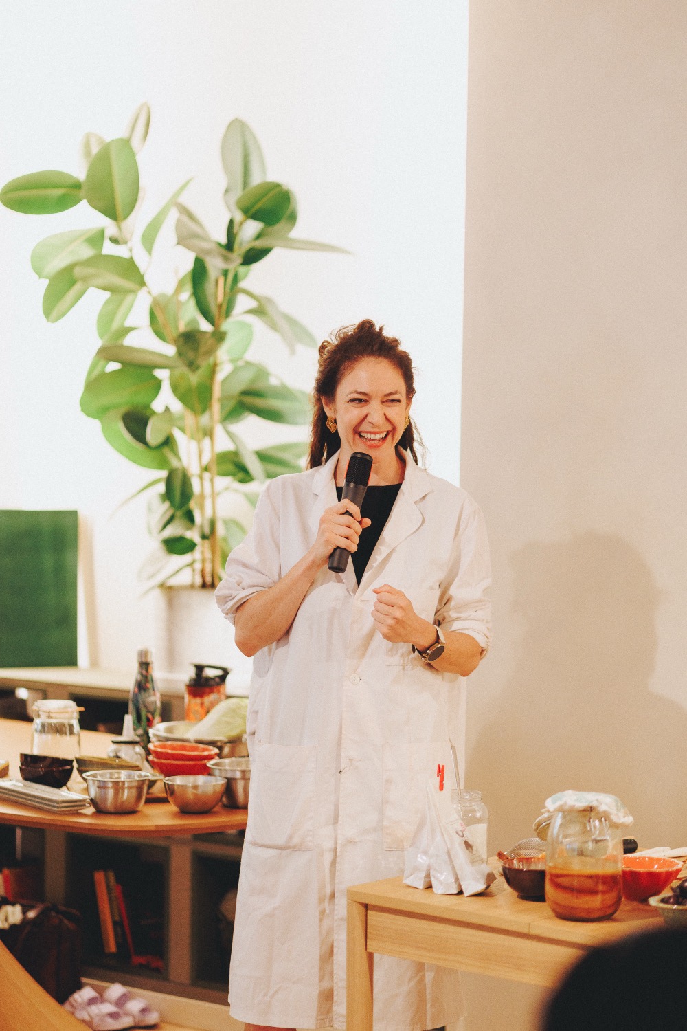 Lucy Antrobus in a lab coat, speaking with a microphone at a live fermentation demonstration